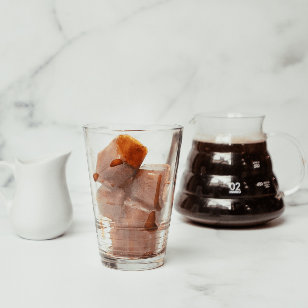 Ice cubes made of coffee in a glass beside a coffee pot