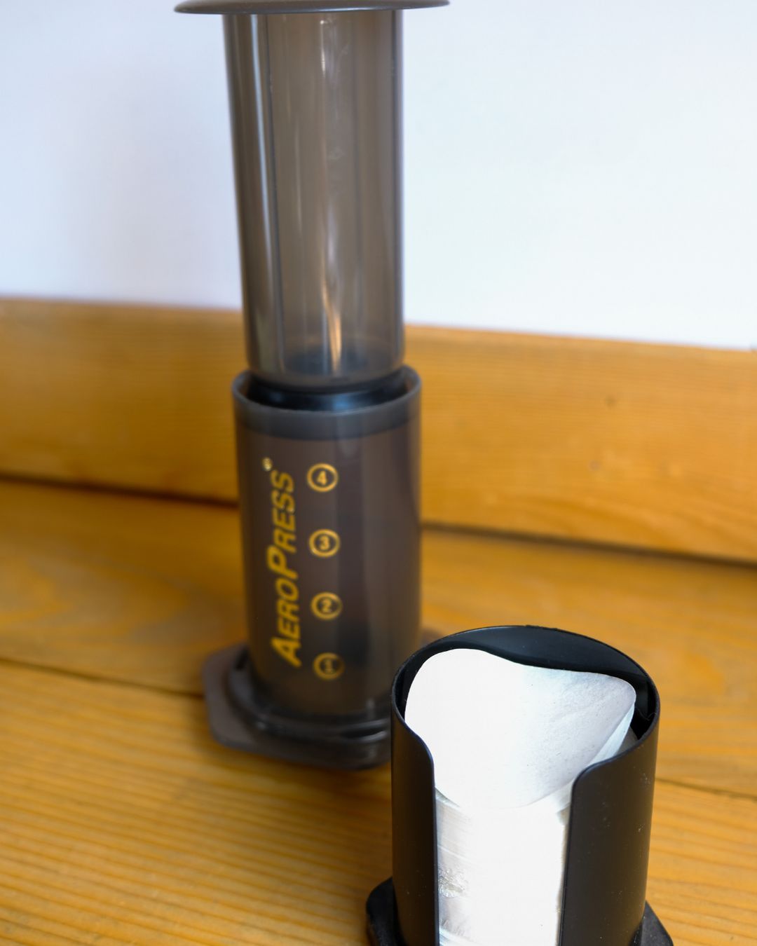 An AeroPress sits on a counter with paper filters that are used to prepare a shot of coffee or espresso