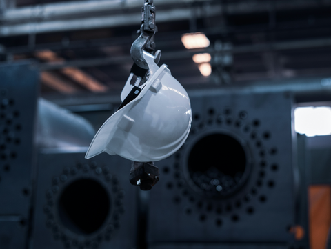 Helmet hanging from a crane, in an industrial manufacturing setting