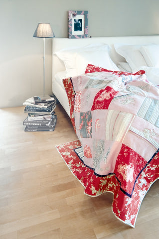 A red and white quilt draped on a bed