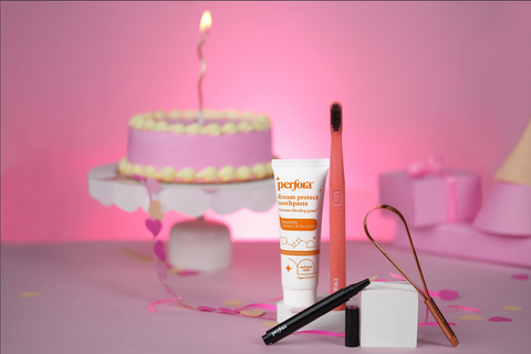 Perfora's electric toothbrush and toothpaste along with the whitening pen with a cake in the background