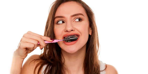 image of a woman brushing her teeth with an activated charcoal toothpaste