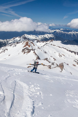 split boarder has his arms raised in joy as he descends the Mazama Glacier on Mount Baker