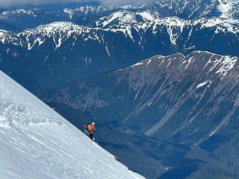 lead splitboard guide rides on the edge of a Ridgeline with the valley far below