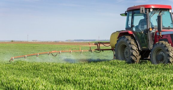 Tractor spraying a hay crop with preservatives