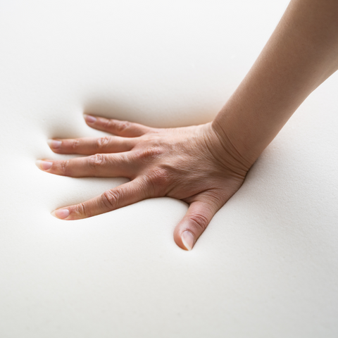 A hand pressing into a memory foam sample, demonstrating the contouring properties and pressure-relieving qualities of memory foam, a popular choice for caravan mattresses.