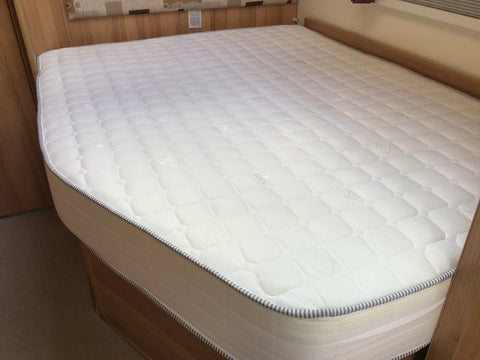 Nearside mattress with angled cut, fitting snugly into its bed base inside a caravan.