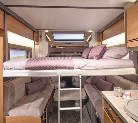 Colorful image of a cozy drop-down bed with stylish bedding, featuring a comfortable mattress, plush pillows, and a warm blanket, set up for a restful night's sleep in a motorhome or campervan