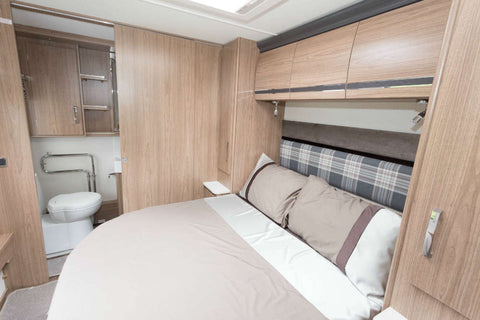 The bed is positioned transversely (widthwise) across the caravan, with the foot of the bed almost touching opposite walls of the caravan