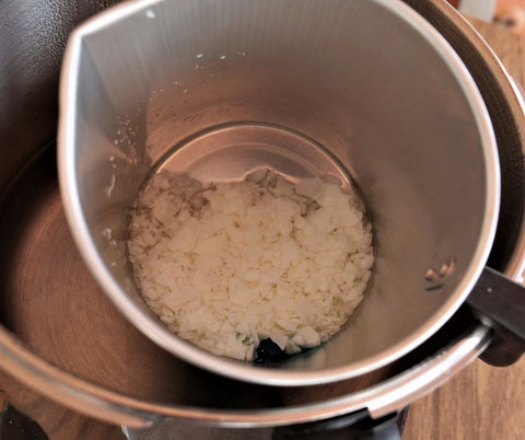 metal wax pot hanging off of a pot full of water with wax melting