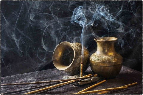 gold pots on a table with incense sticks burning clouds of smoke