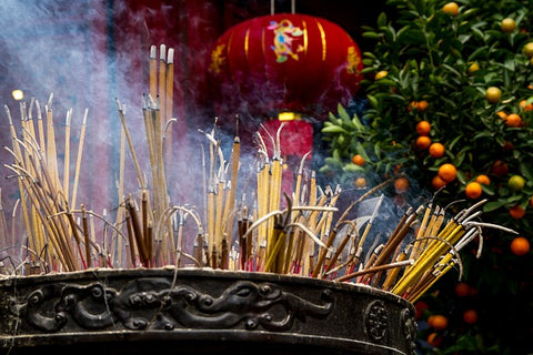 a stone cauldron holding a large amount of smouldering and smoking incense sticks of various sizes