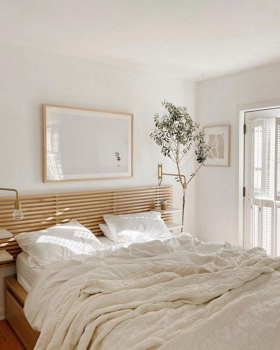 sunny Scandinavian bedroom with a horizontal wood slat headboard and light colored bedding