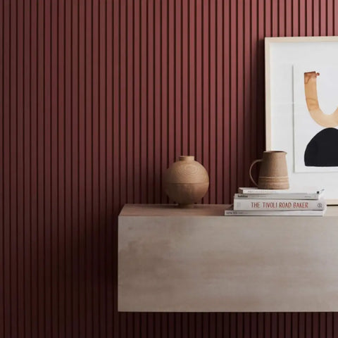 Minimalist decor on a maroon wood wall panel, exemplifying types of decorative wood wall panels in modern interior design