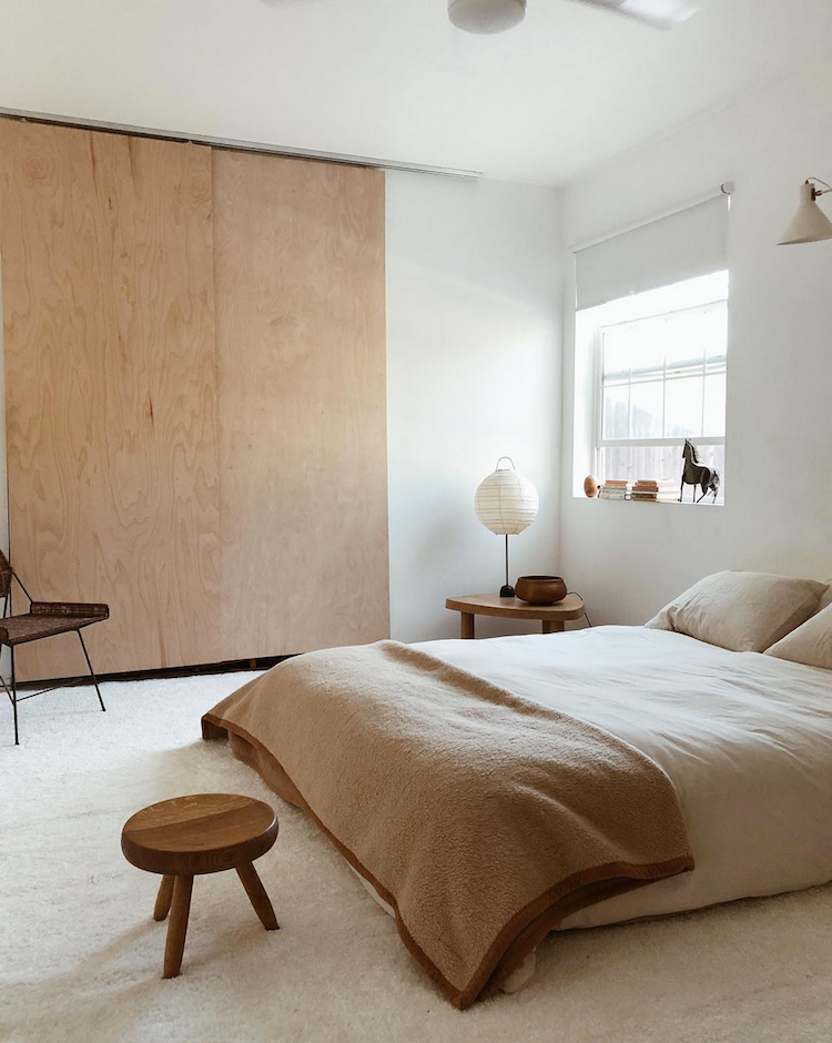 japandi bedroom with plywood closet doors and light-colored bedding