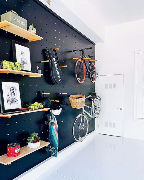 painted black pegboard with hooks for bicycle and shelving inside home