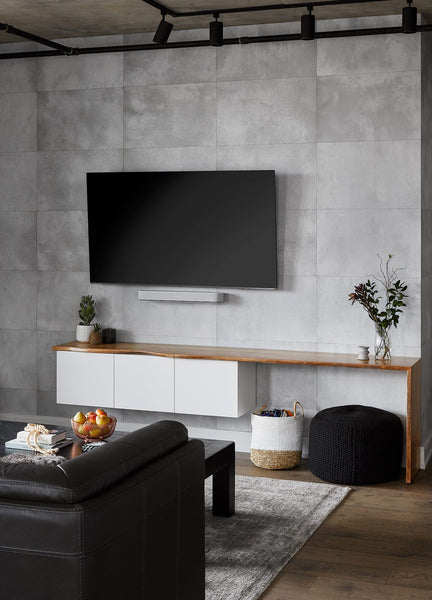 loft-style apartment with a concrete accent wall behind the tv and minimal ceiling track lighting