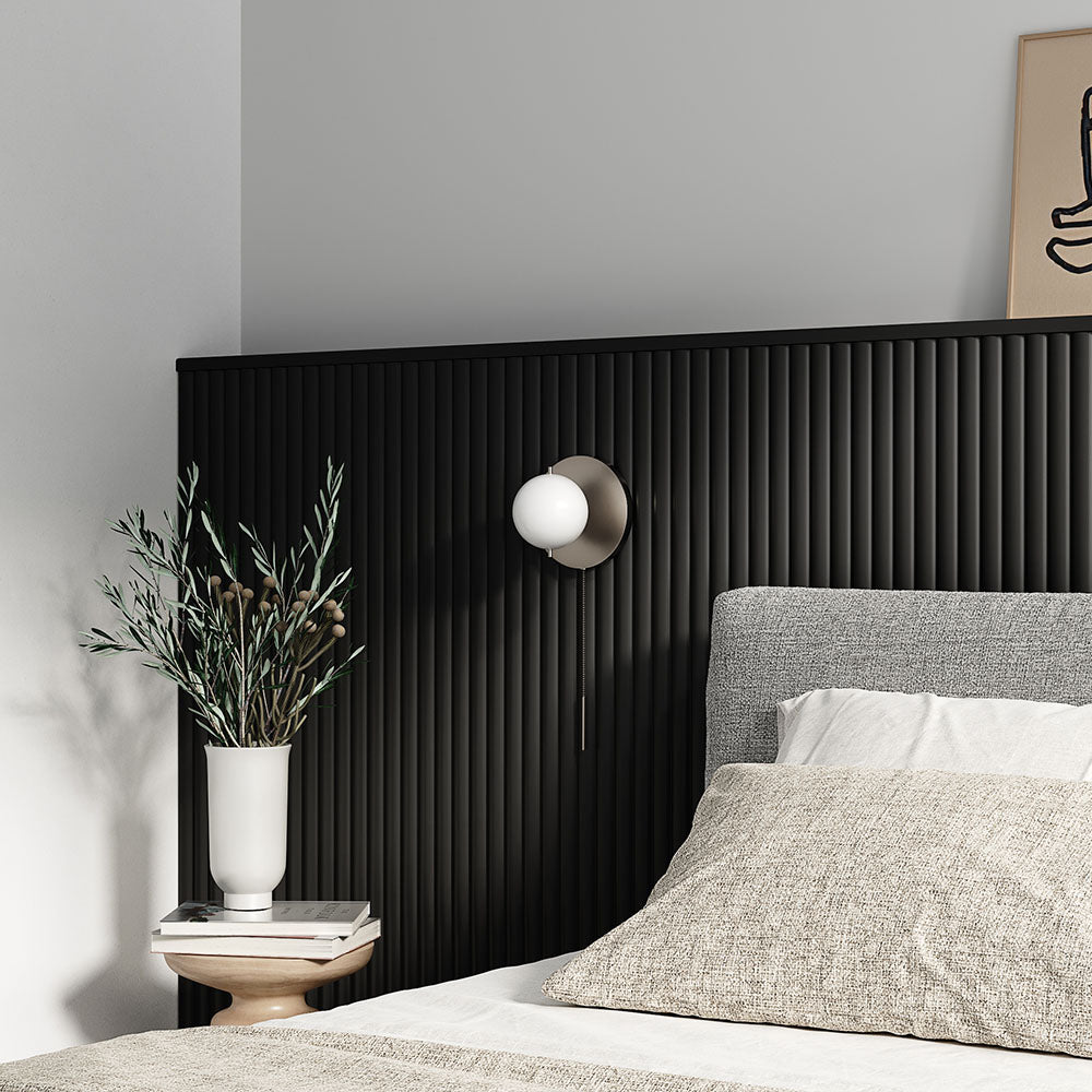 minimalist bedroom with neutral bedding and a black textured half-wall behind the bed