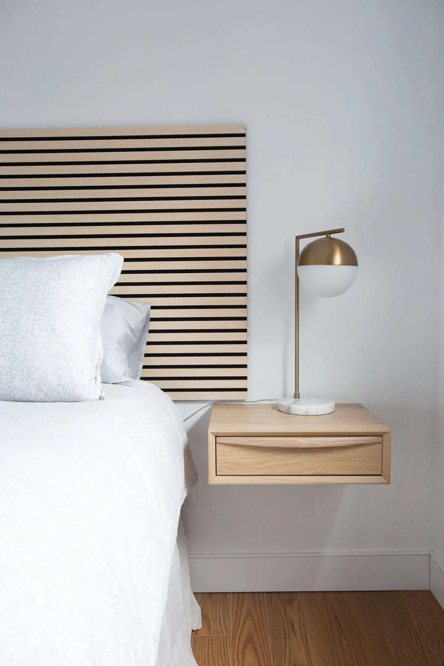 floating bedside table with white sheets and a horizontal oak wood slats headboard