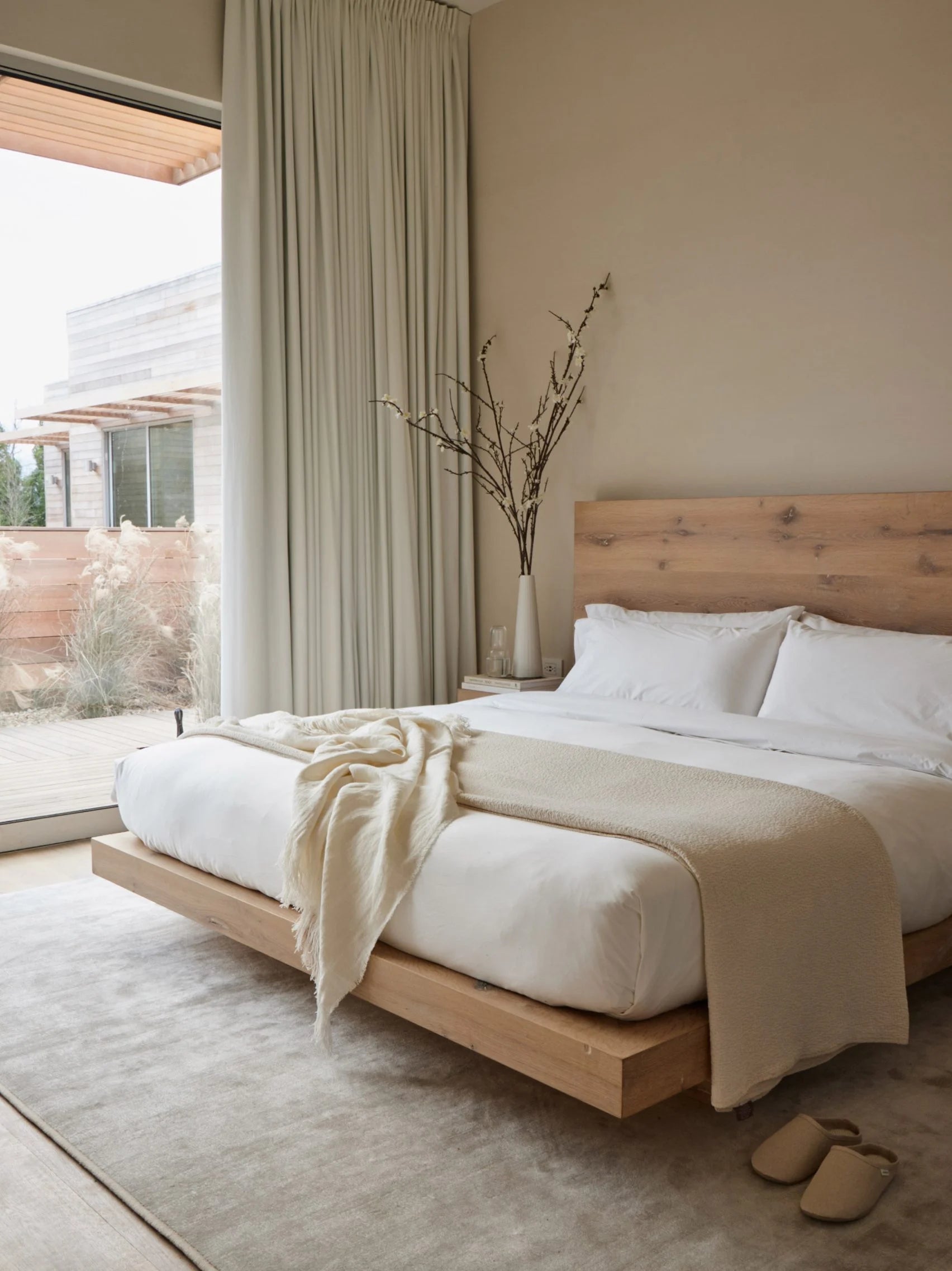 warm bedroom with solid oak bed frame and large window facing outdoor patio