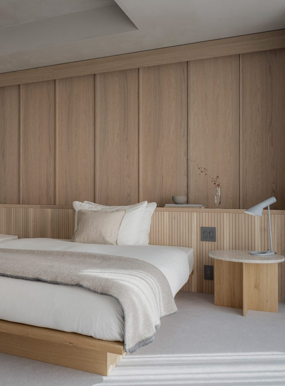 minimalist japanese bedroom with oak wood wall panels behind bed