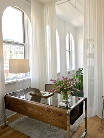 long white flowing loft style curtains in apartment home office with midcentury desk and lamp