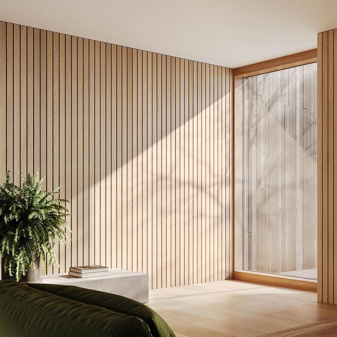 A minimalist home interior with floor-to-ceiling wooden slat walls, a large window allowing natural light to flood the space, a green plant, and a simple concrete bench with books.