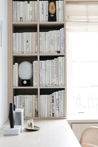 minimalist light wood bookshelf full of white books in scandinavian style home office