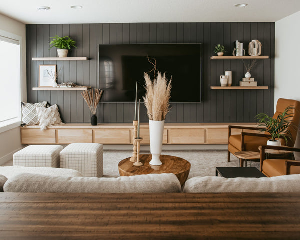 modern rustic living room with black beadboard wall panelling behind tv with natural oak floating shelves and a custom media console