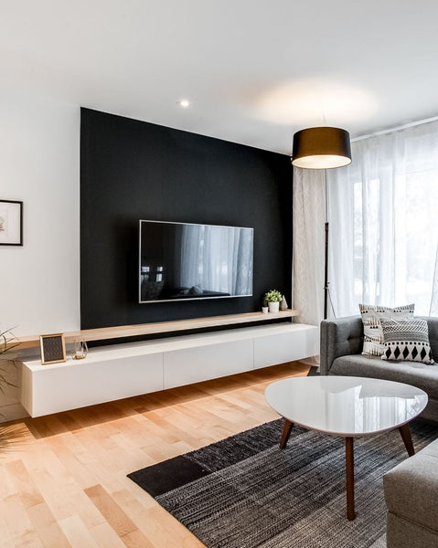 modern living room with oak hardwood floors and a painted black accent wall behind the tv with a floating media unit