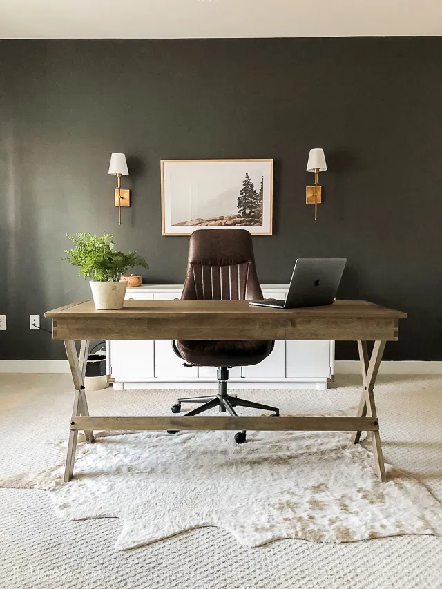 black accent wall in home office with desk and sconces