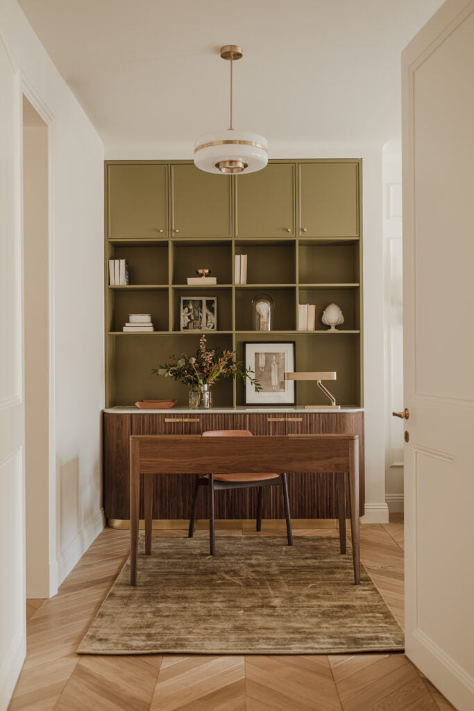 home office with green built-in shelving and a custom wood desk