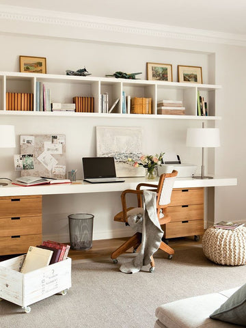 Scandinavian home office with a bookshelf a white rug a white desk and wooden accents