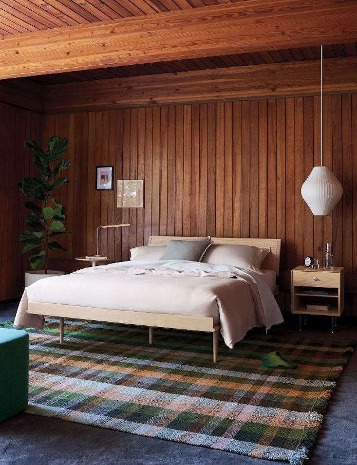 mid-century bedroom with floor to ceiling wood wall panelling and rustic bedding with vintage light fixtures