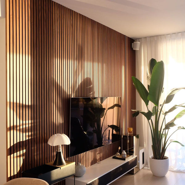 mid-century modern living room with a vertical wood slat accent wall behind the tv with birds of paradise houseplant and a mushroom lamp