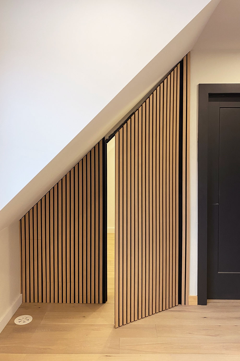 white oak wood slat hidden door in modern home with light oak wood flooring