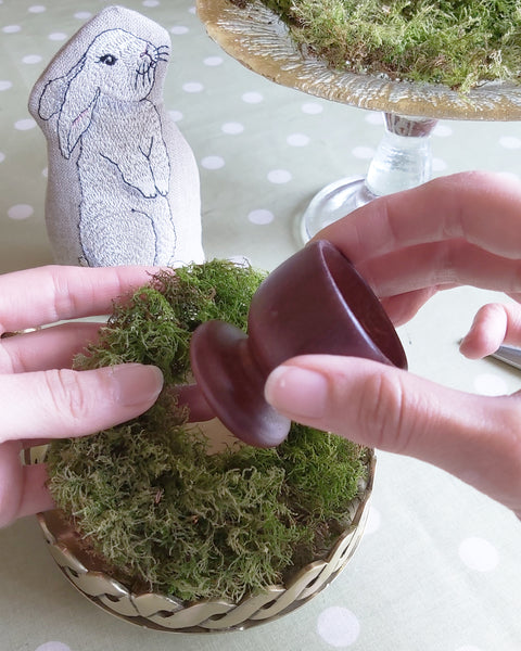 Slotting an egg cup into the centre of a dried moss ring for a table centre piece