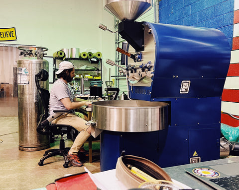 Adam sits at the coffee roaster as he begins to start roasting a batch of coffee.