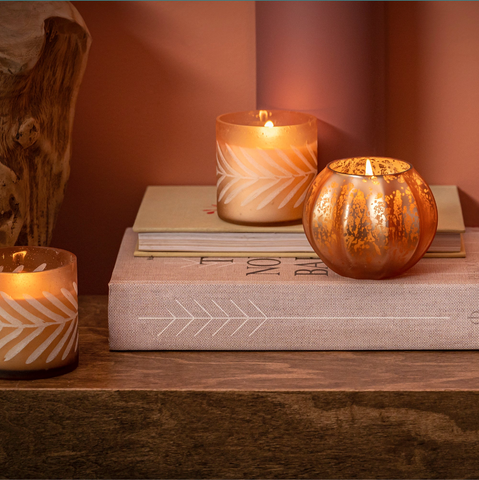 pumpkin shaped candle burning on book