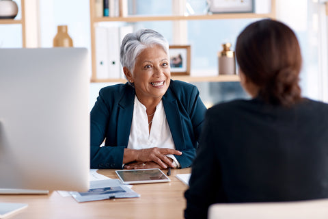 Employee talking and sitting across the desk from her boss