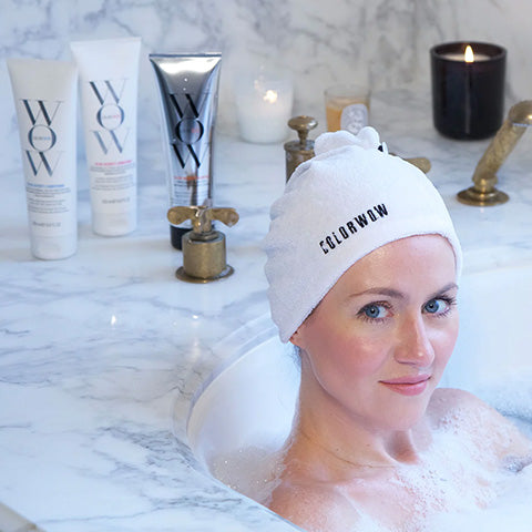 woman sitting in bathtub with white towel on her head