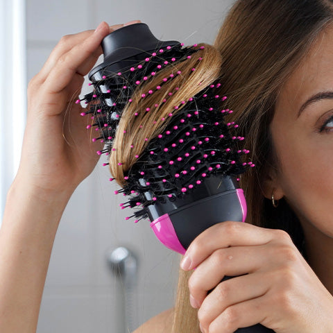 woman blow drying her hair with a blow dry brush