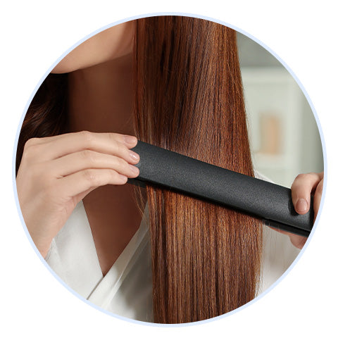 close-up of a woman flat ironing her auburn hair