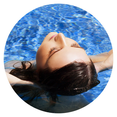 woman tipping her head back in blue swimming pool water