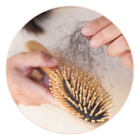 person picking dark hair out of a hairbrush