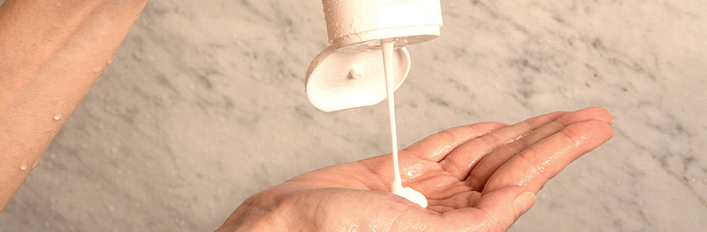 person squeezing conditioner onto their hand