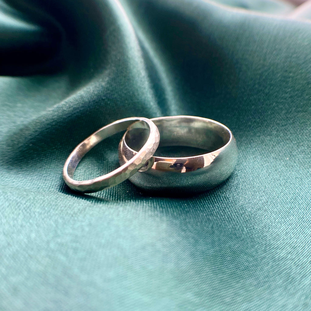 2 sterling silver wedding rings on dark green satin