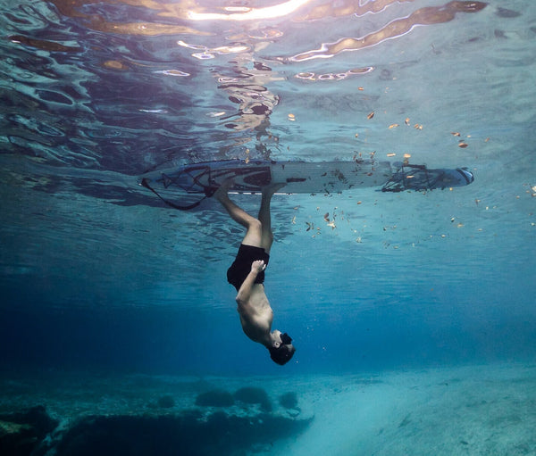 Man riding BLACKFIN standup paddle board upside down underwater