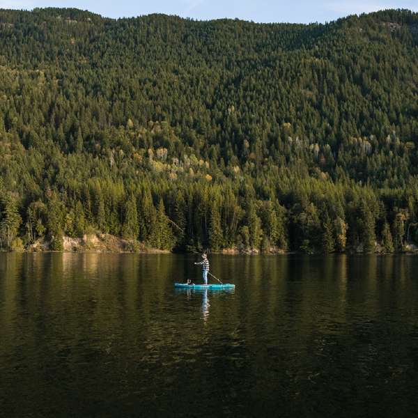 Person paddling on the BLACKFIN standup paddle board on rocky shoreline