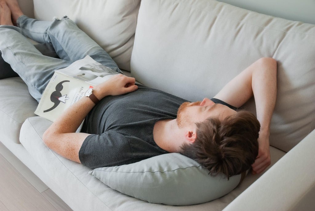Mężczyzna relaksujący się i robiący power nap na lnianej poduszce gryczanej WELLB w kształcie księżcywa